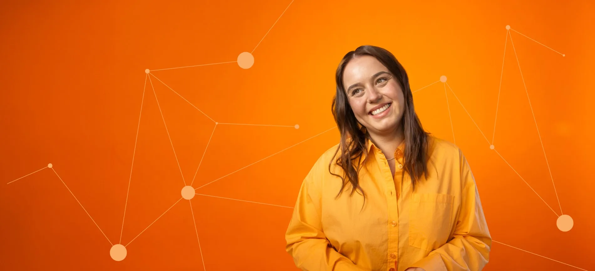 Junge Frau in orangem Hemd lächelt vor orangefarbenem Hintergrund mit vernetzten IT-Grafikelementen.