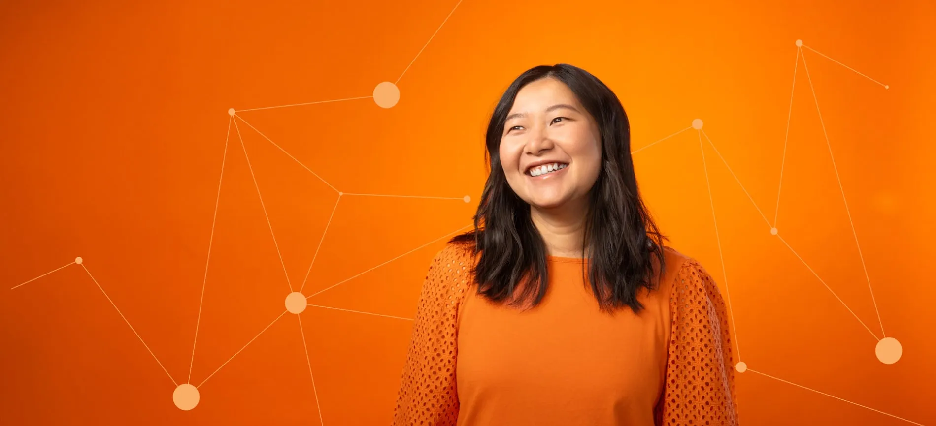 Junge Frau lächelt vor orangefarbenem Hintergrund mit IT-Netzwerk-Motiven, einladend für Deine Karriere bei 4flow SE.