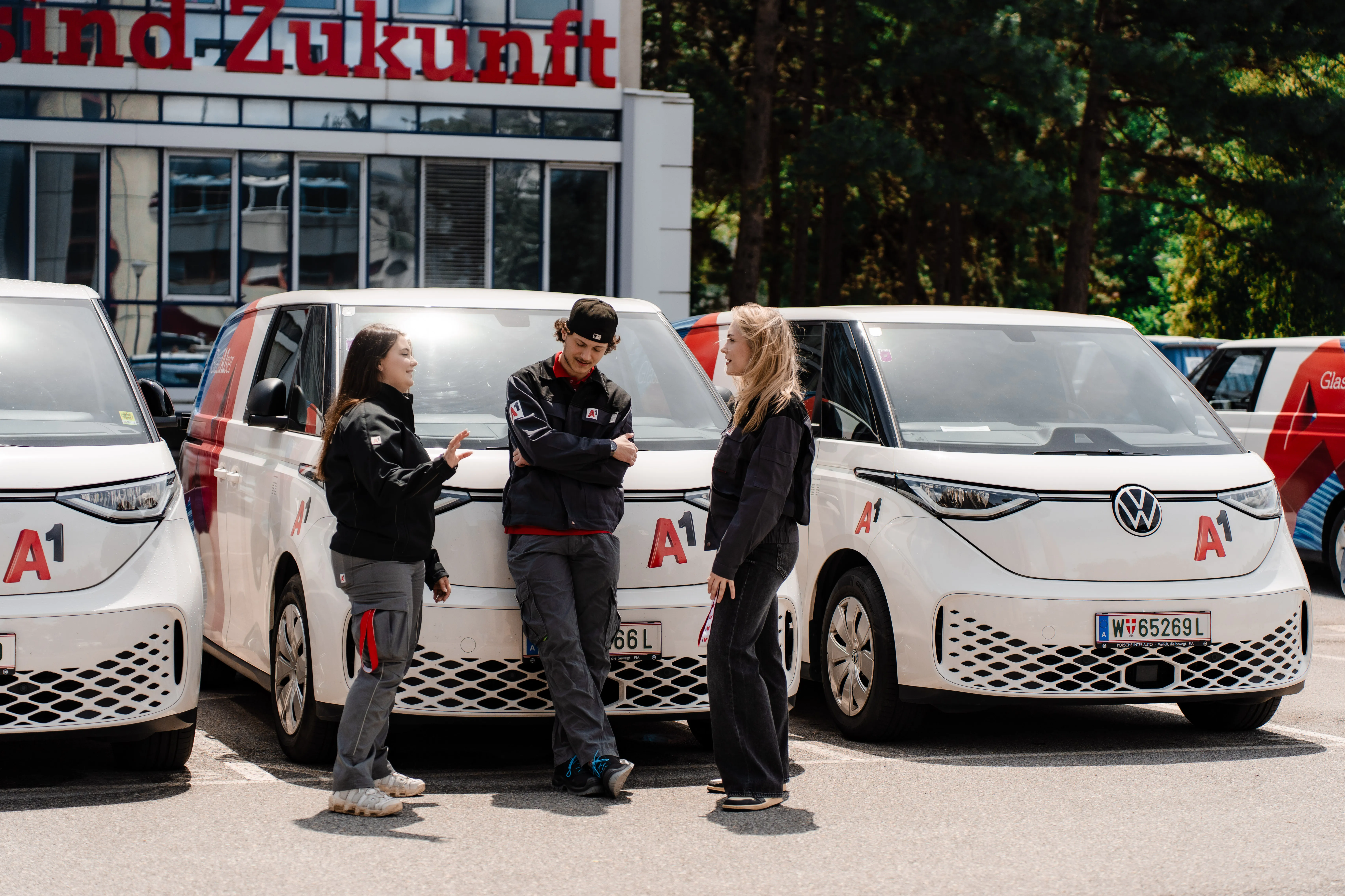 Zwei junge A1-Mitarbeitende lächeln im Telekommunikations-Shop in die Kamera. Du bist willkommen im Team.