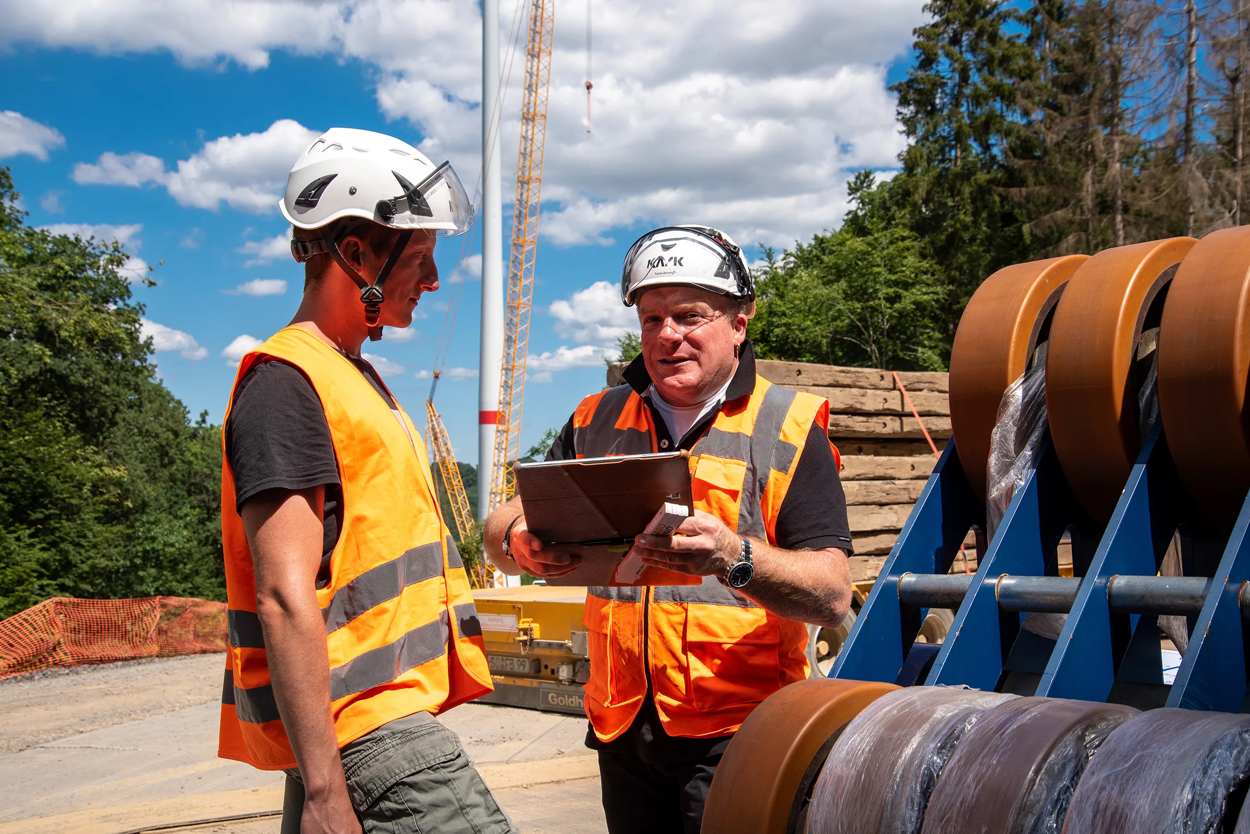 Bauingenieure mit Helm und Tablet koordinieren Arbeiten an einem Windkraftprojekt