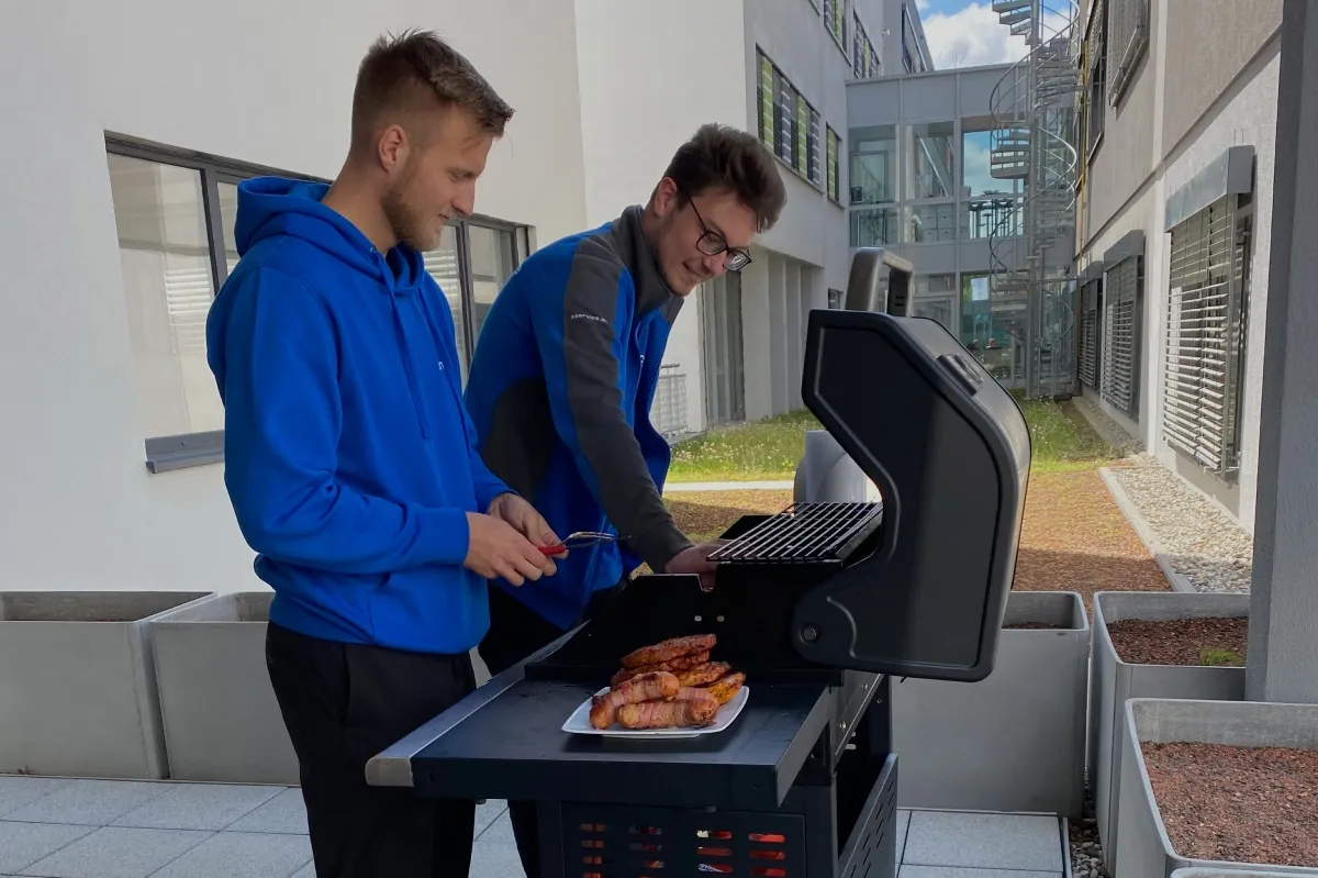 Zwei junge Mitarbeiter am grillen