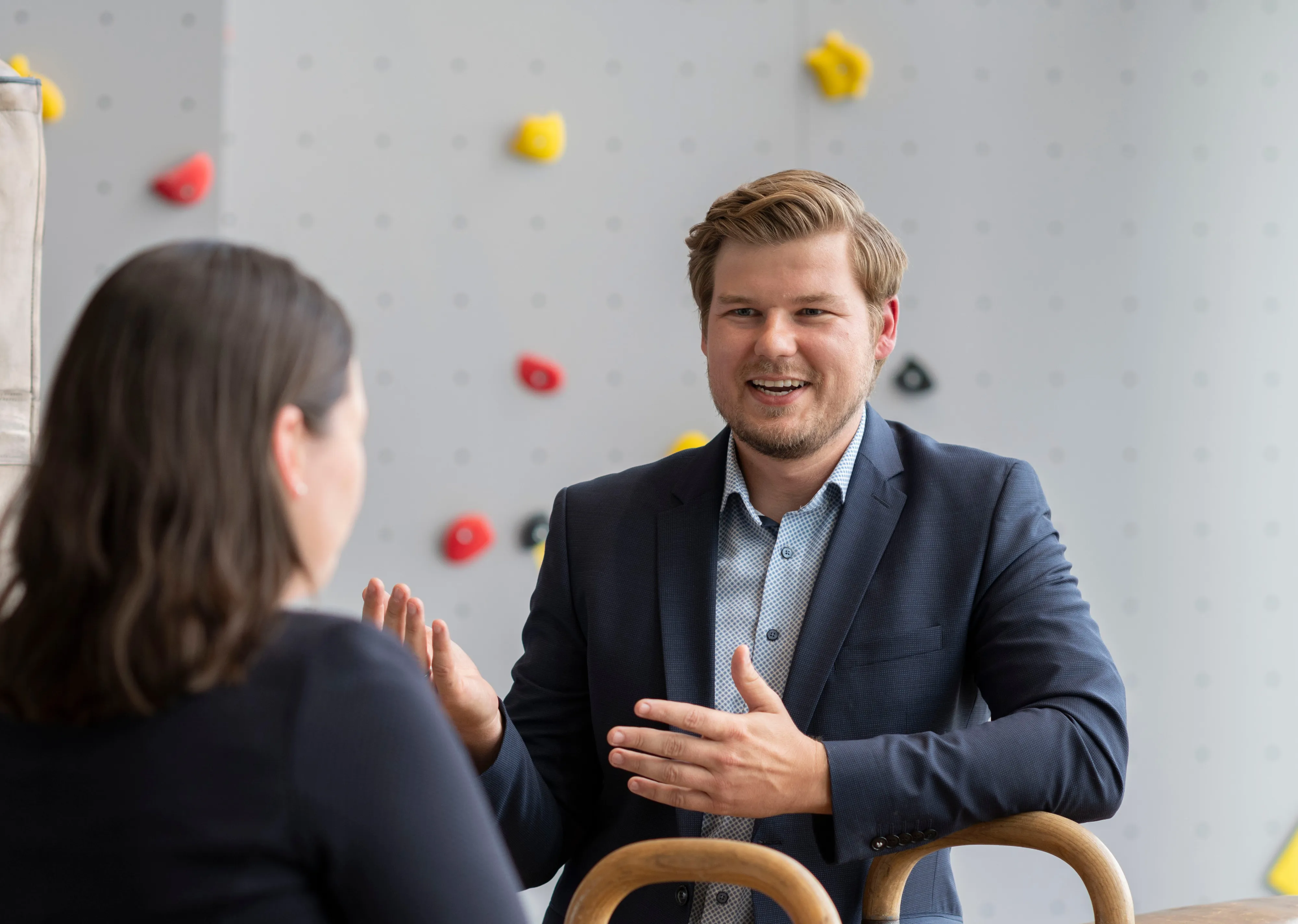 Ein Mann im Anzug unterhält sich lächelnd mit einer Frau in einem modernen Bürosetting bei ARAG SE.