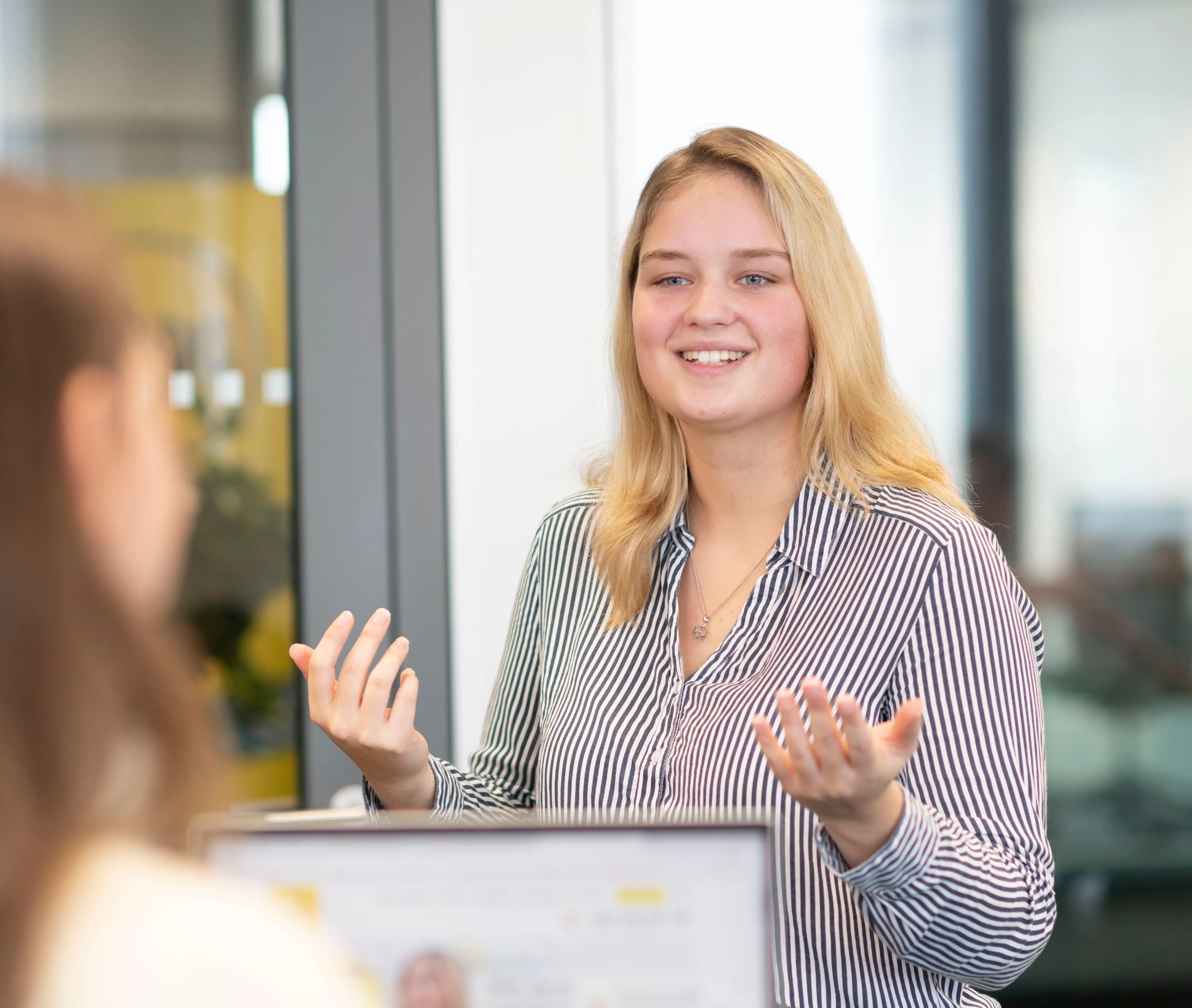 Eine junge Frau in einem Meeting bei ARAG SE spricht lächelnd mit einer Kollegin.