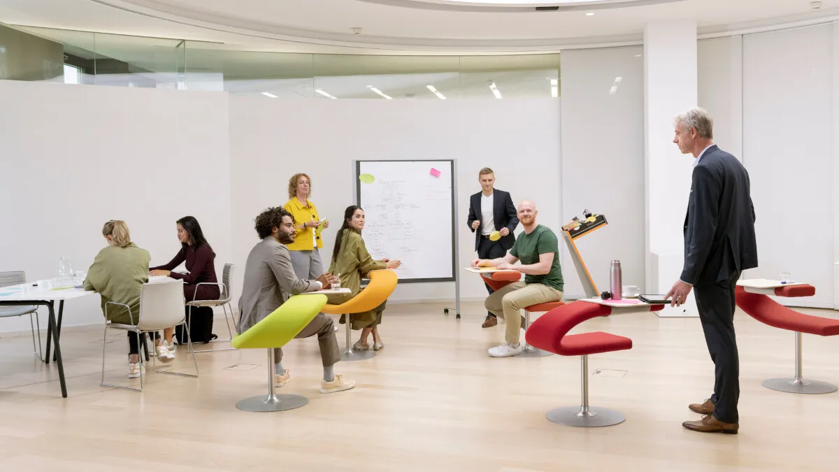 Eine Gruppe von IT-Fachleuten diskutiert in einem modernen, hellen Konferenzraum bei Atruvia AG vor einem Whiteboard.