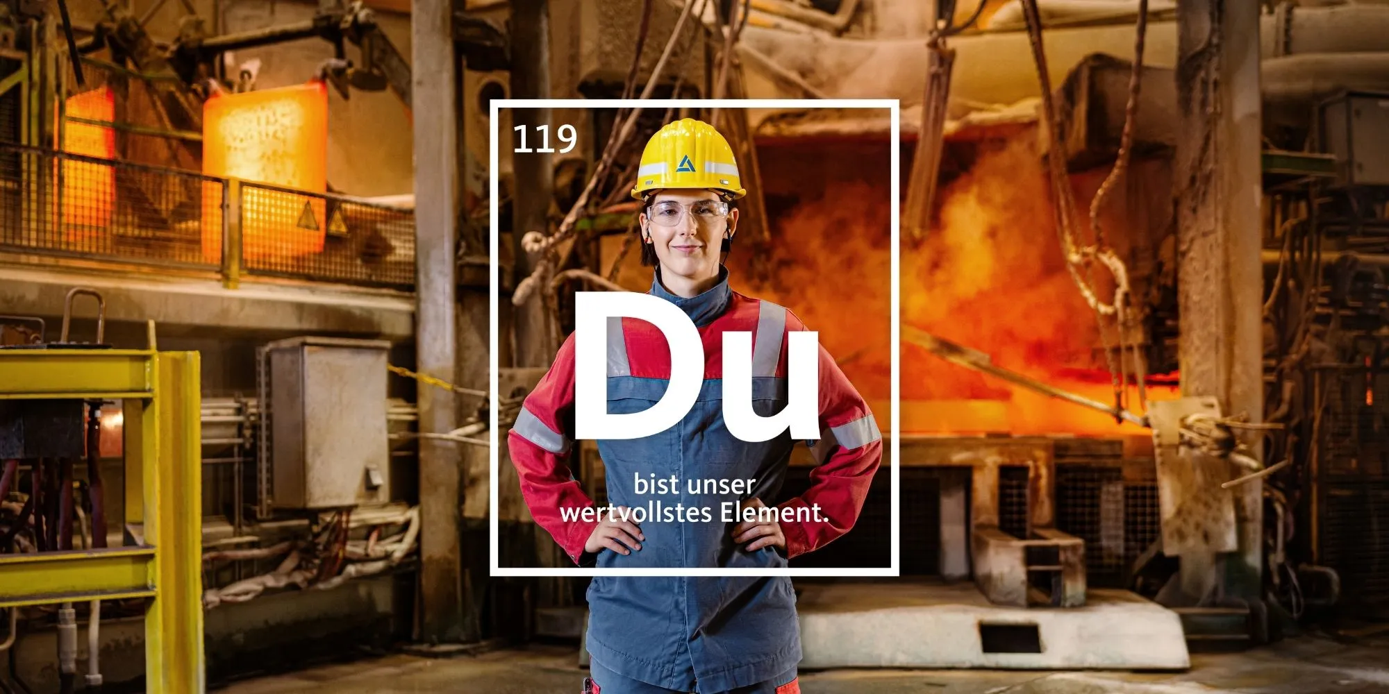 Junge Frau steht lächelnd mit Notizbuch im Büroflur; Text betont, dass Du für Aurubis das wichtigste Element bist.
