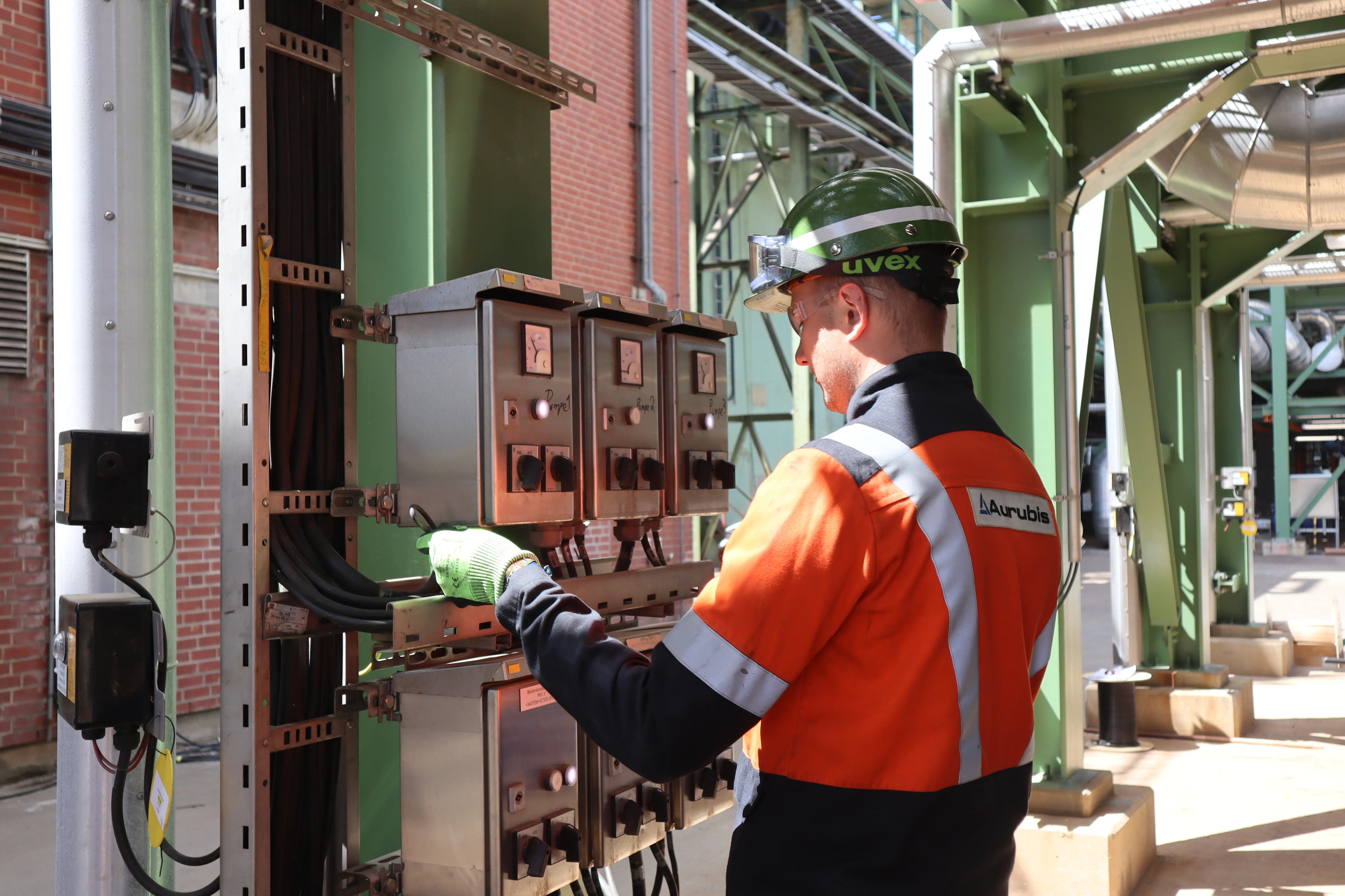 Ein junger Mitarbeiter zeichnet ein technisches Schaltbild auf eine Glasscheibe im modernen Labor von Aurubis AG.