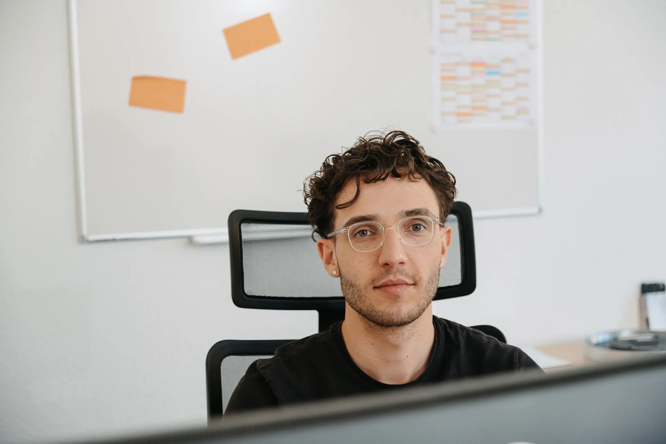 Fünf lächelnde AWB-Mitarbeiter in orangefarbener Arbeitskleidung sitzen gemeinsam im Fahrerhaus eines Müllwagens.