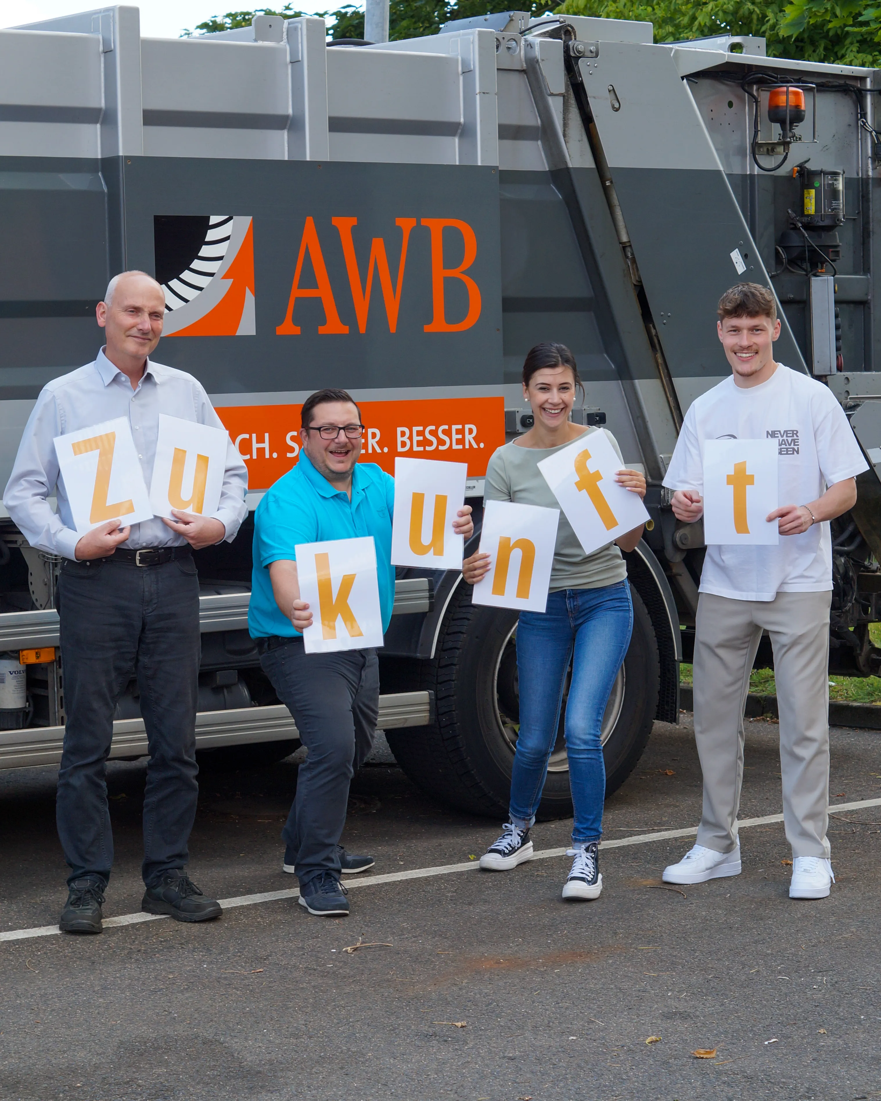 Ein AWB-Mitarbeiter im orangefarbenen Shirt sitzt lächelnd am Steuer eines Müllfahrzeugs und blickt aus dem Fenster.