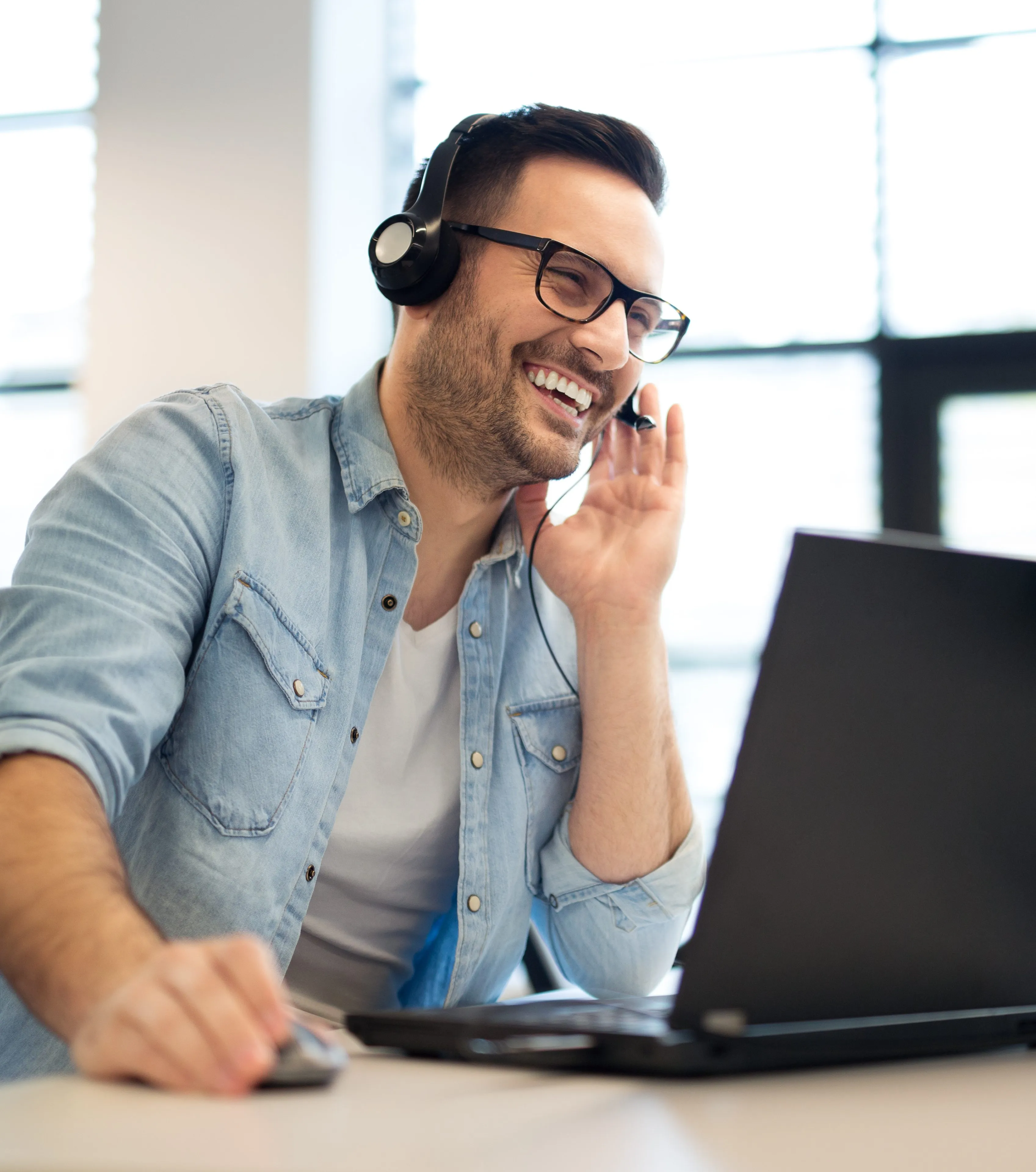 Mann an Laptop mit Headset