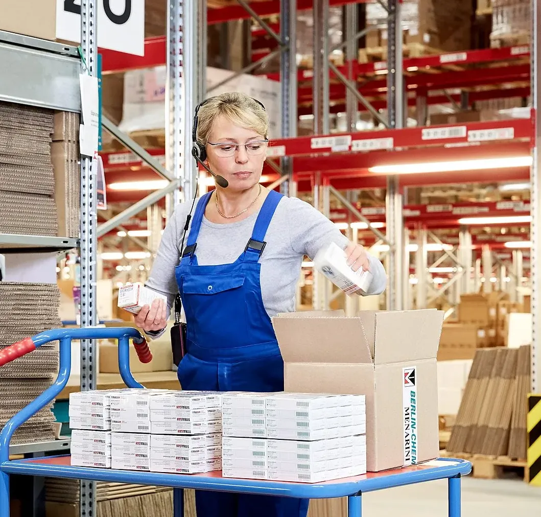 Eine Wissenschaftlerin im weißen Laborkittel arbeitet mit einem Mikroskop im Labor von Berlin-Chemie Menarini.