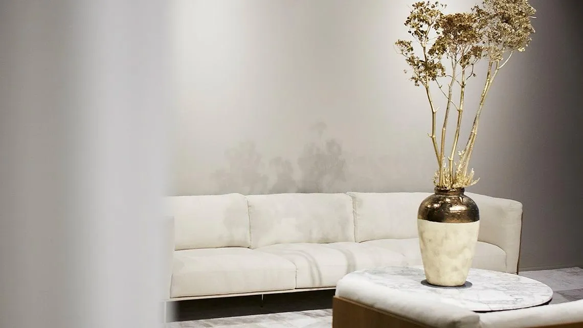 Heller, moderner Lounge-Bereich mit gemütlichem Sofa und stilvoller Vase – Dein Arbeitsplatz bei Betty Barclay Group.