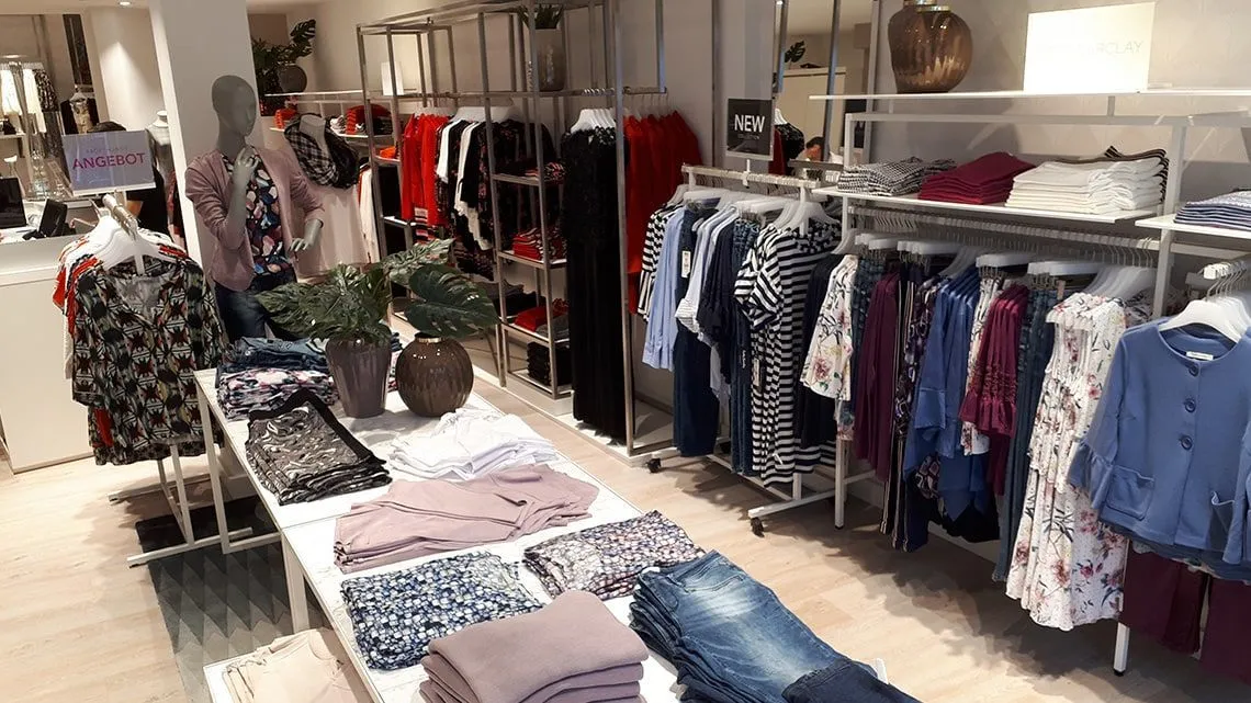 Moderner Betty Barclay Store mit neatly gefalteter Damenmode, Kleiderständern und freundlicher Einkaufsatmosphäre.