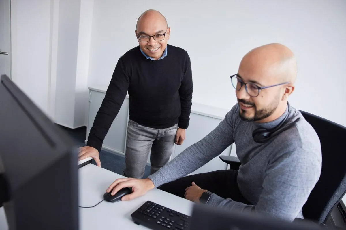 Zwei Kollegen arbeiten gemeinsam am Computer im modernen Büro der Betty Barclay Group.
