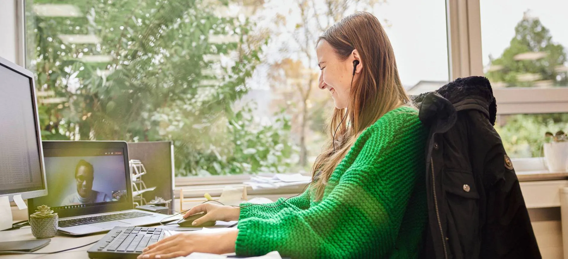 Junge Frau im Büro beim Videocall, lächelt und arbeitet am Computer – moderne Arbeitswelt bei Betty Barclay Group.