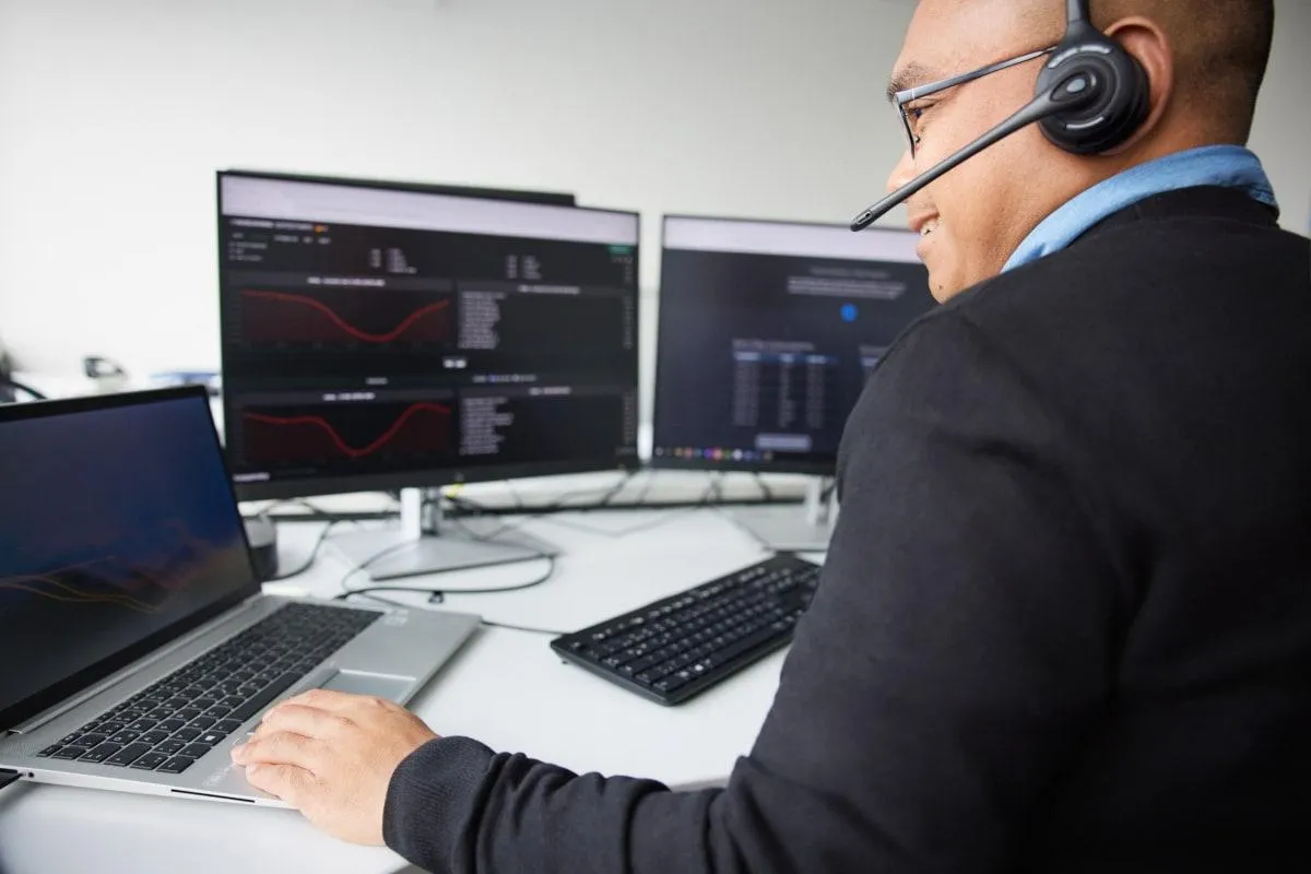 Du arbeitest im modernen Büro am Computer mit Headset und analysierst Daten für die Betty Barclay Group im Einzelhandel.