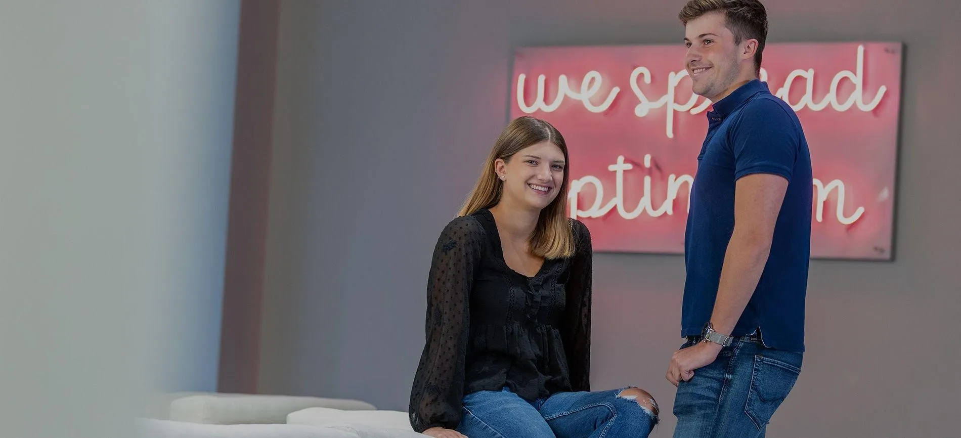 Zwei junge Mitarbeitende der Betty Barclay Group lachen gemeinsam in modernem Büroambiente.