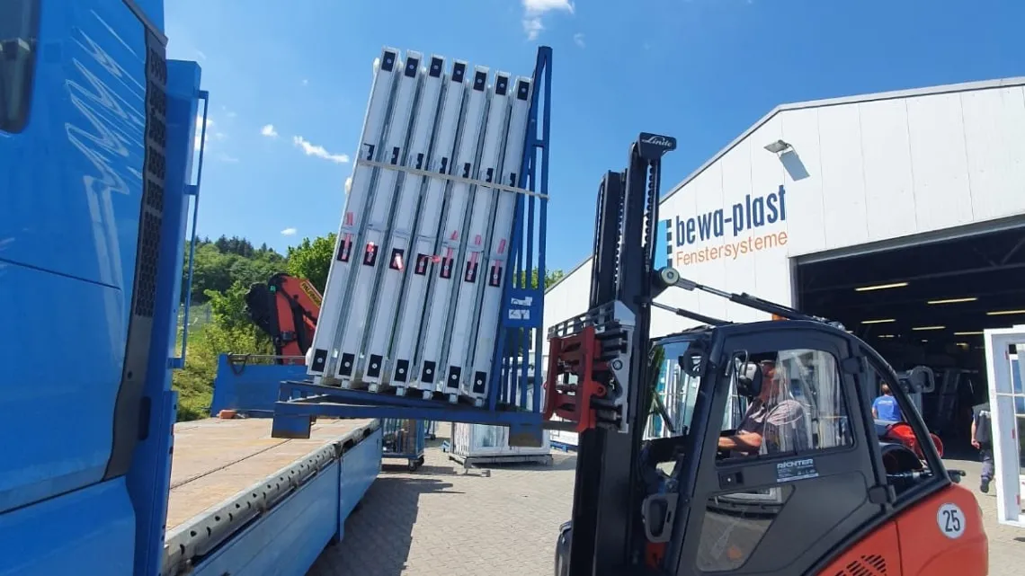 Ein Gabelstapler lädt Fensterrahmen auf einen LKW vor der Halle von bewa-plast Beck GmbH Fenstertechnik.