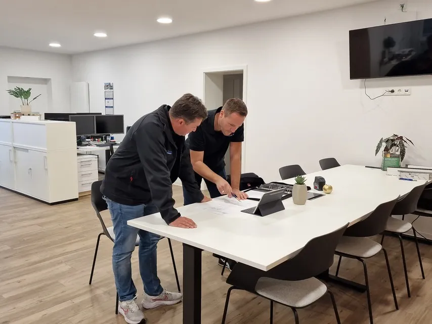Zwei Kollegen besprechen gemeinsam Pläne an einem Konferenztisch im modernen Büro bei bewa-plast Beck GmbH.