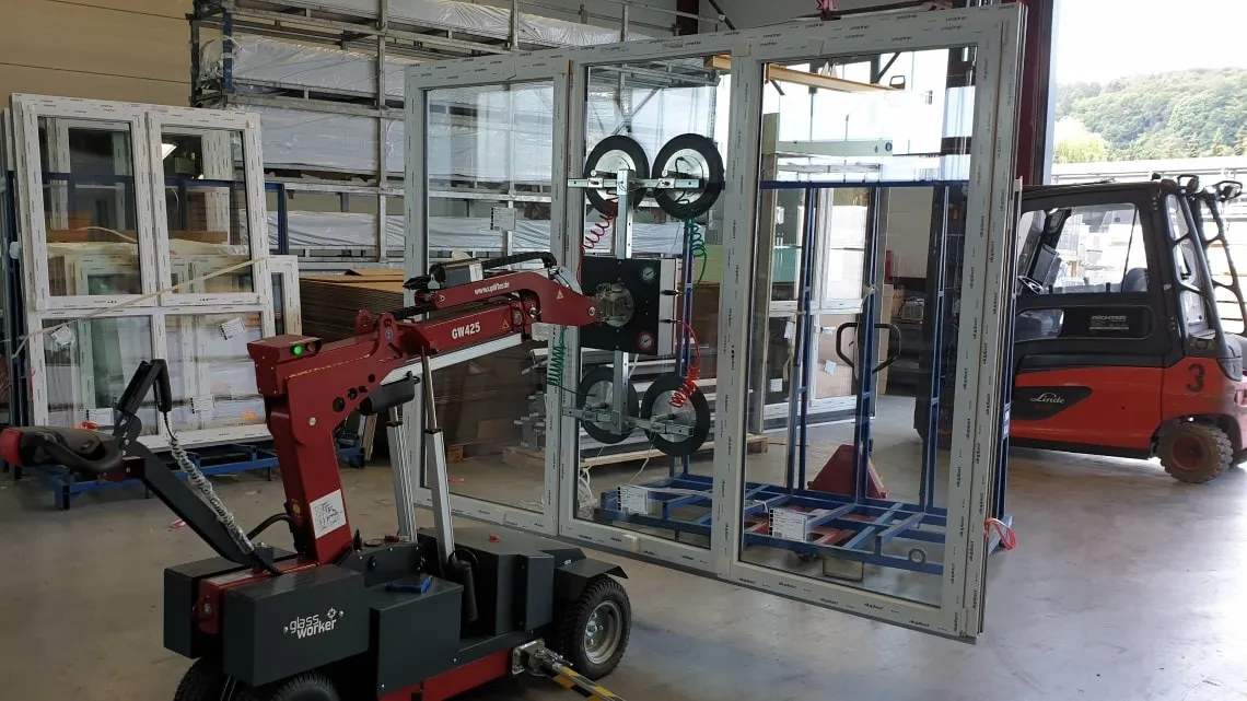 Ein moderner Montage-Roboter hebt ein großes Fensterprofil in der Fertigungshalle bei bewa-plast Beck GmbH.