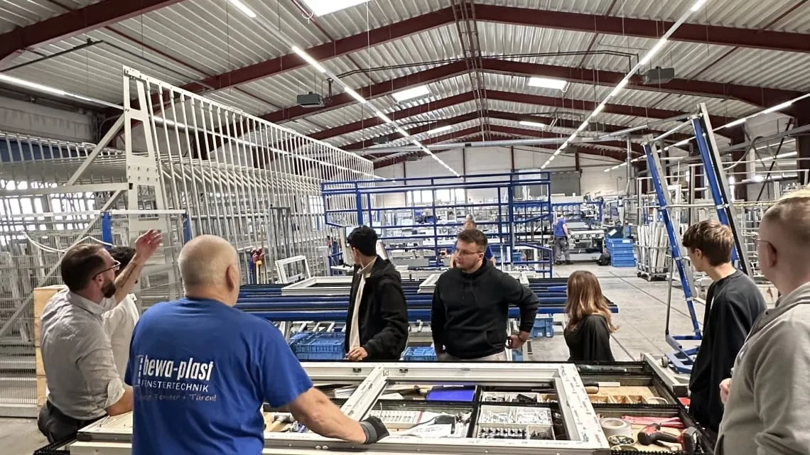 Du siehst ein Team in der Fensterproduktion von bewa-plast Beck GmbH, das gemeinsam an einem Arbeitstisch diskutiert.