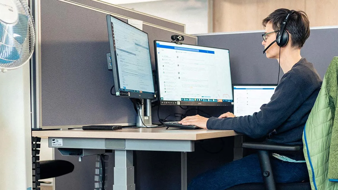 Du arbeitest bei Bike24 im modernen Büro am Schreibtisch, unterstützt Kunden per Headset und Computer.