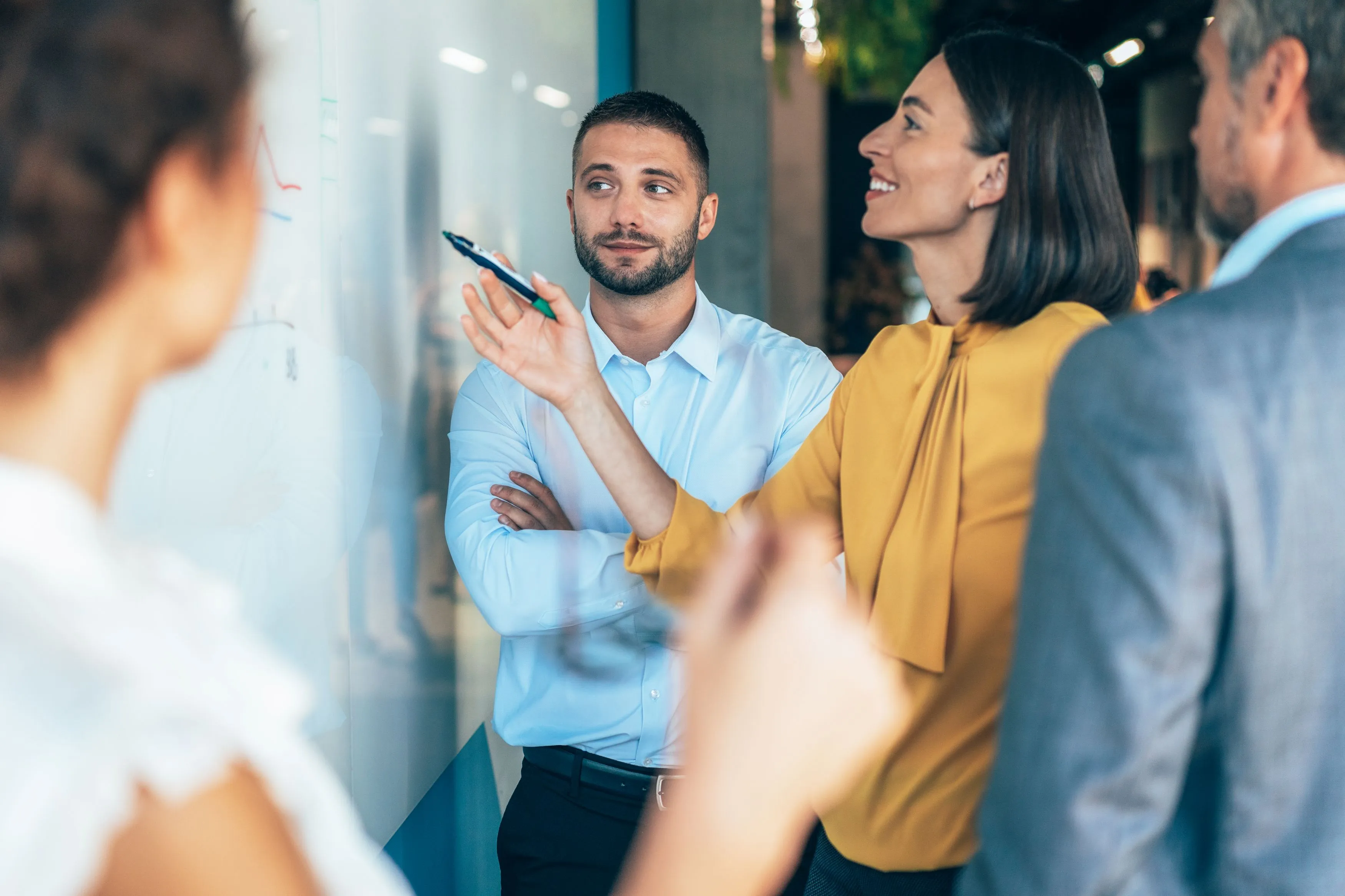 Ein Team bespricht gemeinsam Ideen an einem Whiteboard in einer modernen Arbeitsumgebung im Gesundheitswesen. (iStock / filadendron)