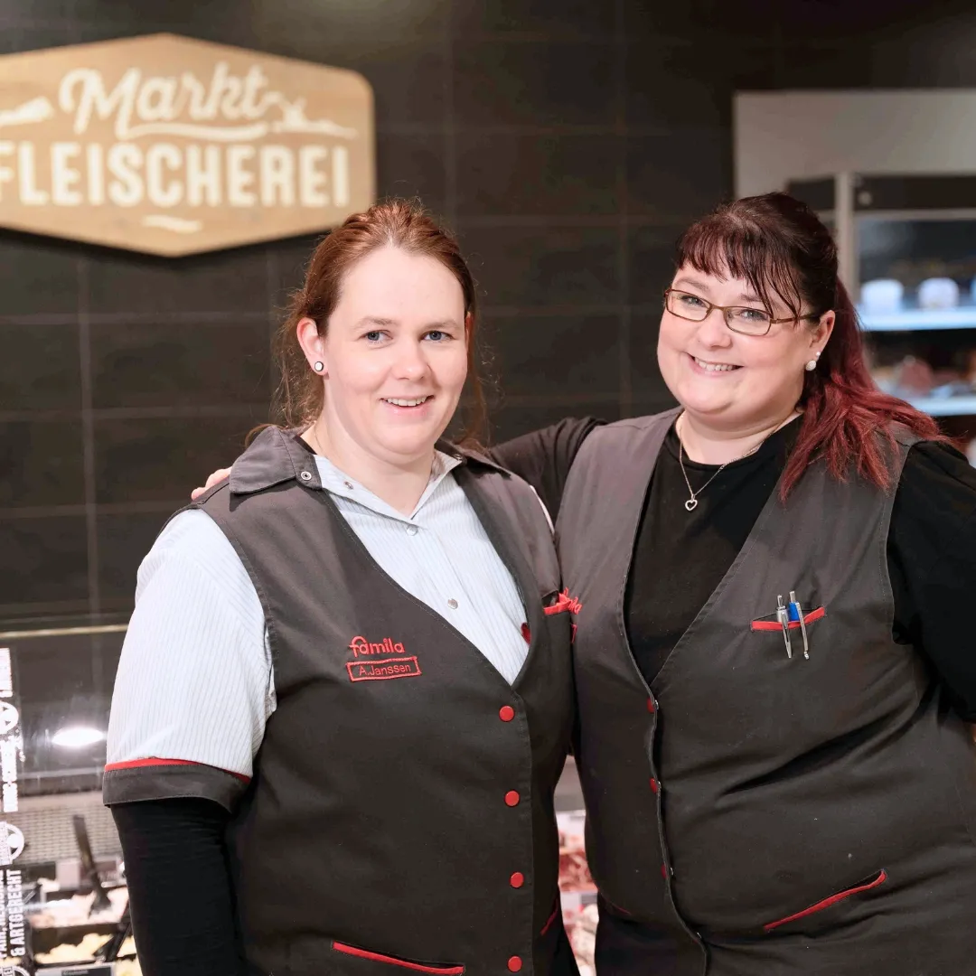 Mitarbeiterin in der Fleischerei von Bünting Unternehmensgruppe zeigt eine Daumen-hoch-Geste vor der Verkaufstheke.
