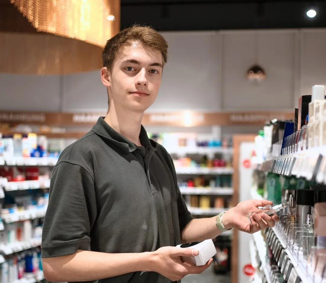 Ein junger Mitarbeiter sortiert Produkte im Regal eines Bünting-Supermarkts.