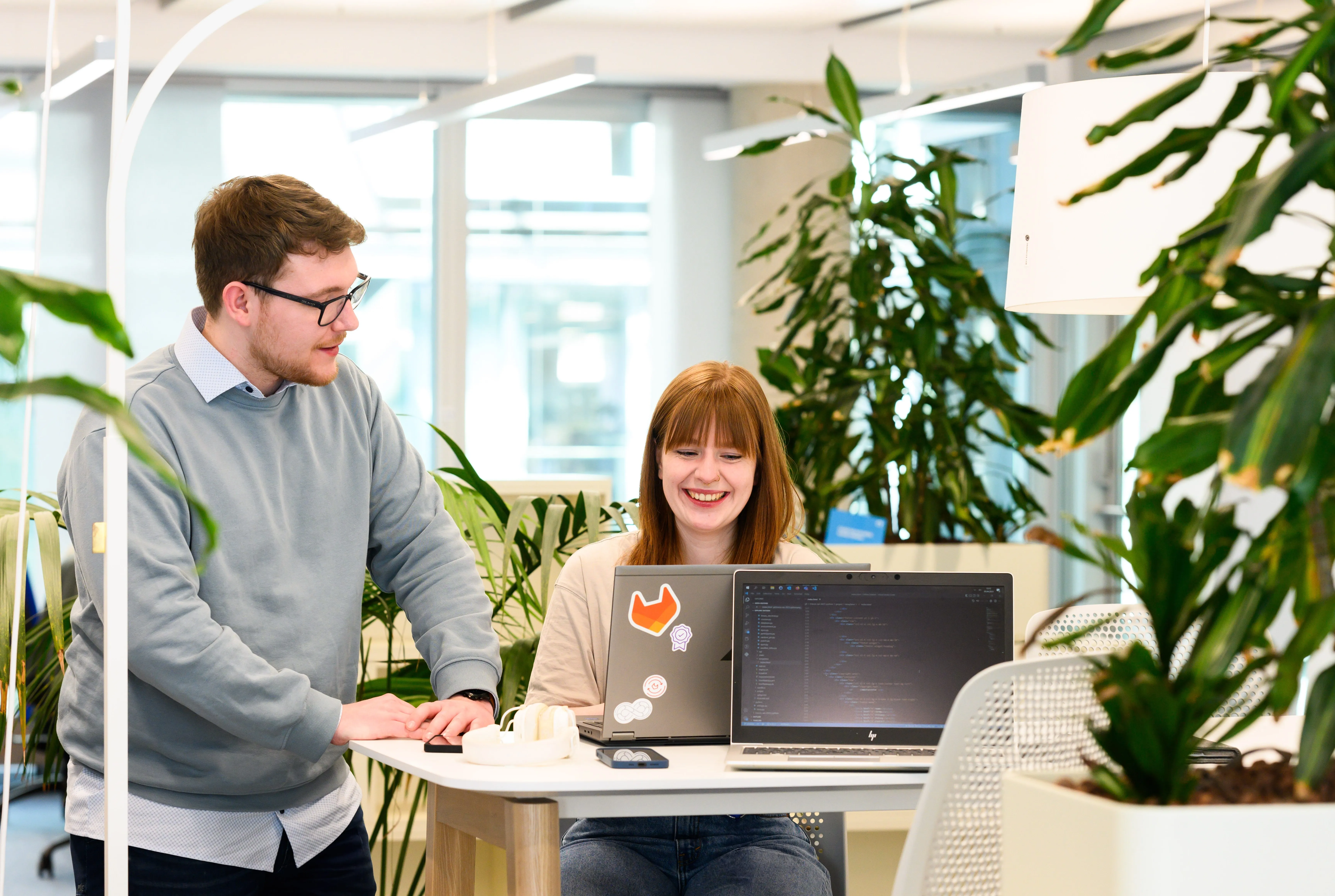 Ein Mann und eine Frau arbeiten gemeinsam an Laptops in einem modernen Büro.