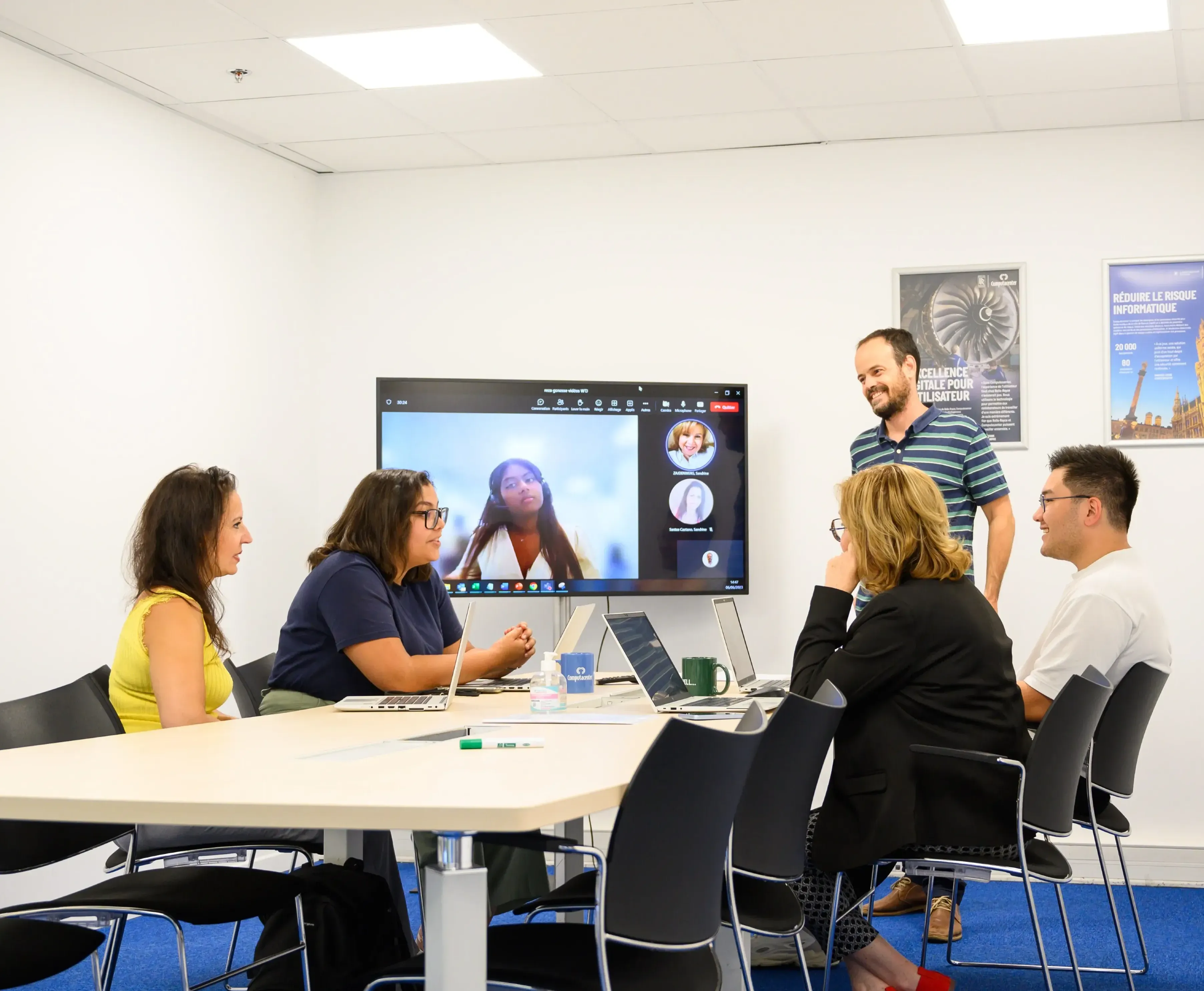 Des collègues discutent autour d'une table avec une réunion vidéo à l'écran chez Computacenter.