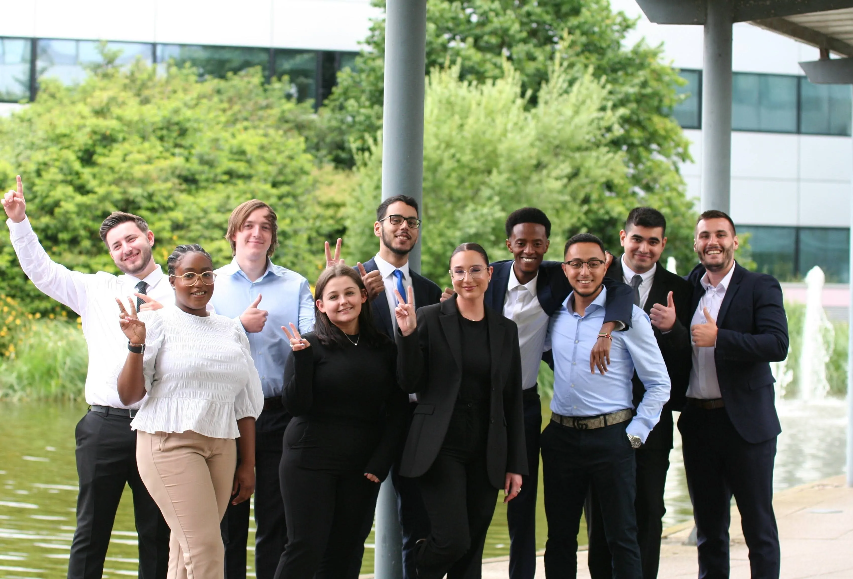 A diverse group of young individuals smiling and posing together for a cheerful group photo outdoors.