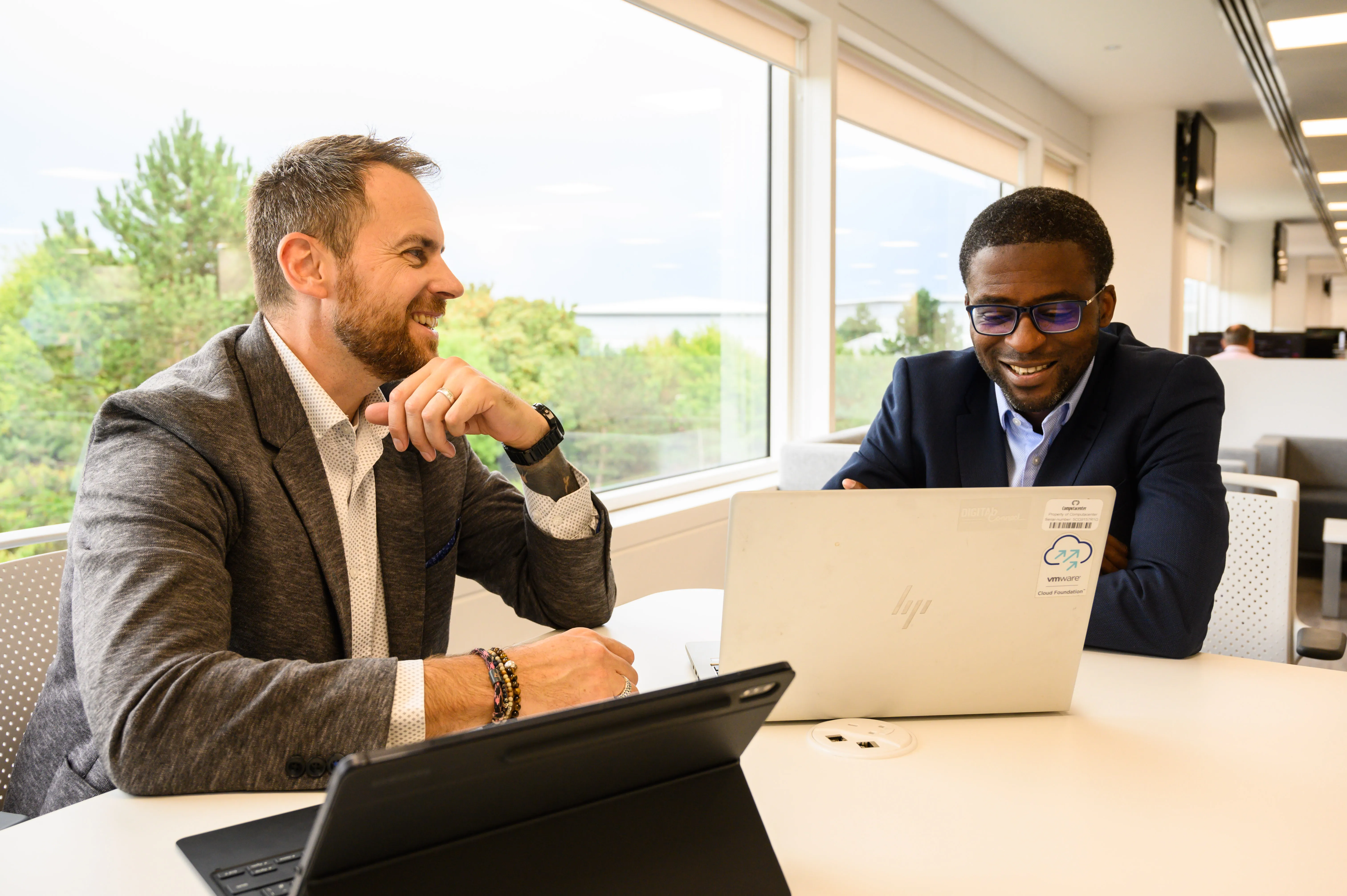 Two IT professionals collaborating on laptops in a bright, modern office at Computacenter AG & Co. oHG.