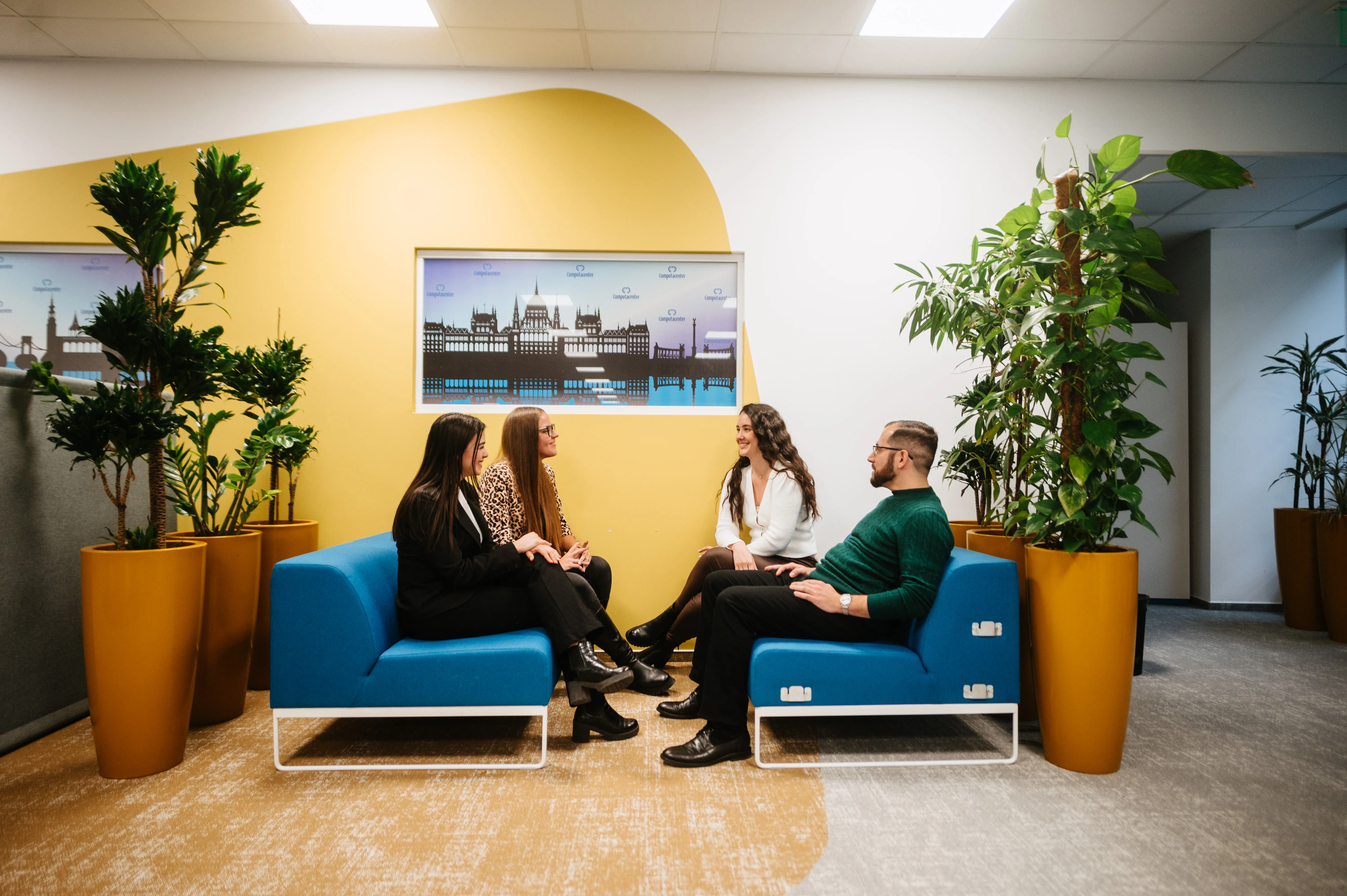Office building of Computacenter with large glass windows, surrounded by greenery and a vibrant tree in bloom.