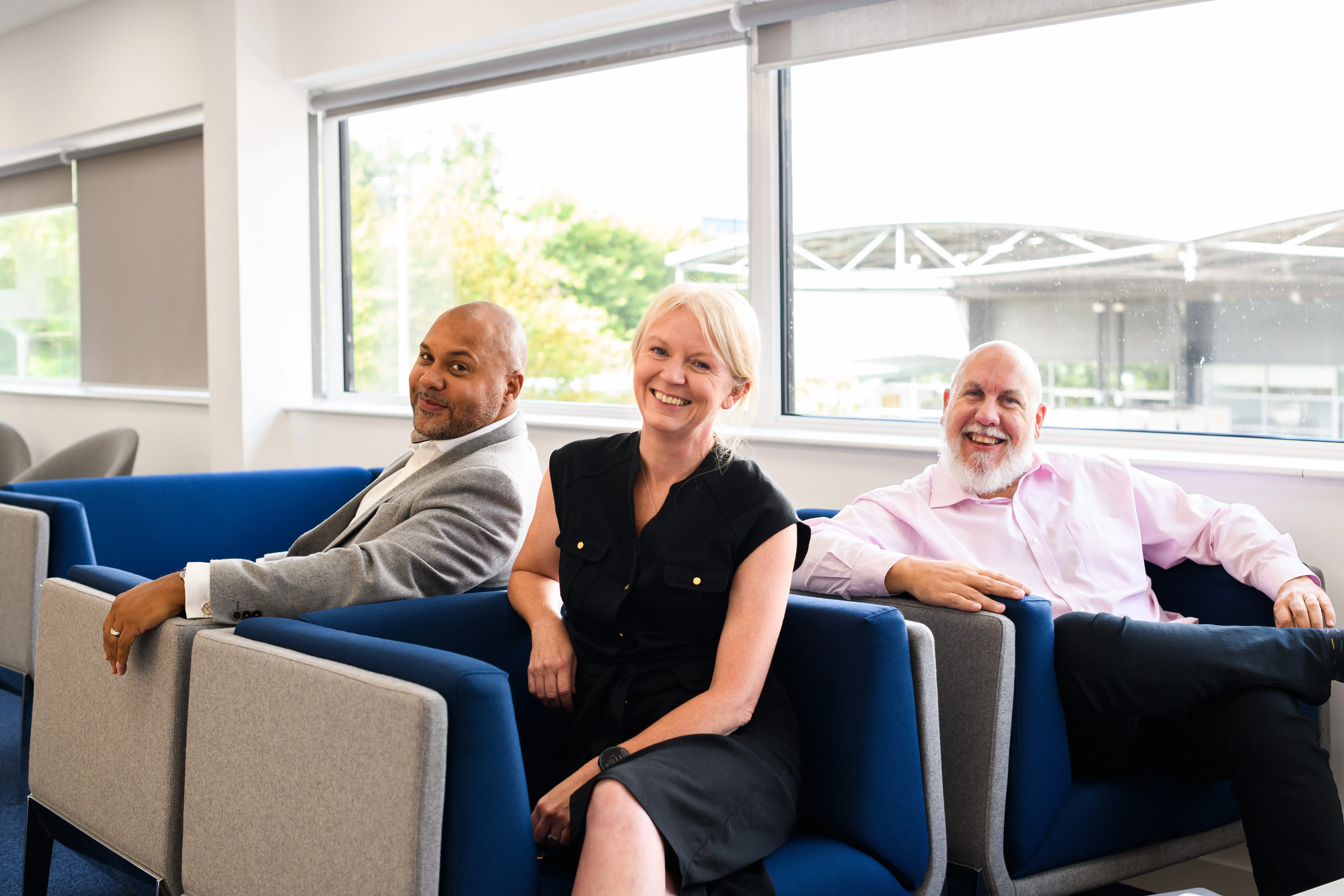 Three cheerful colleagues relaxing in an office lounge at Computacenter AG & Co. oHG, embodying a vibrant and friendly work environment.