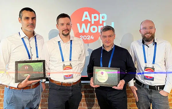 Vier Männer mit Auszeichnungen stehen lächelnd vor einem „App World 2024“-Logo auf einer Karrieremesse.