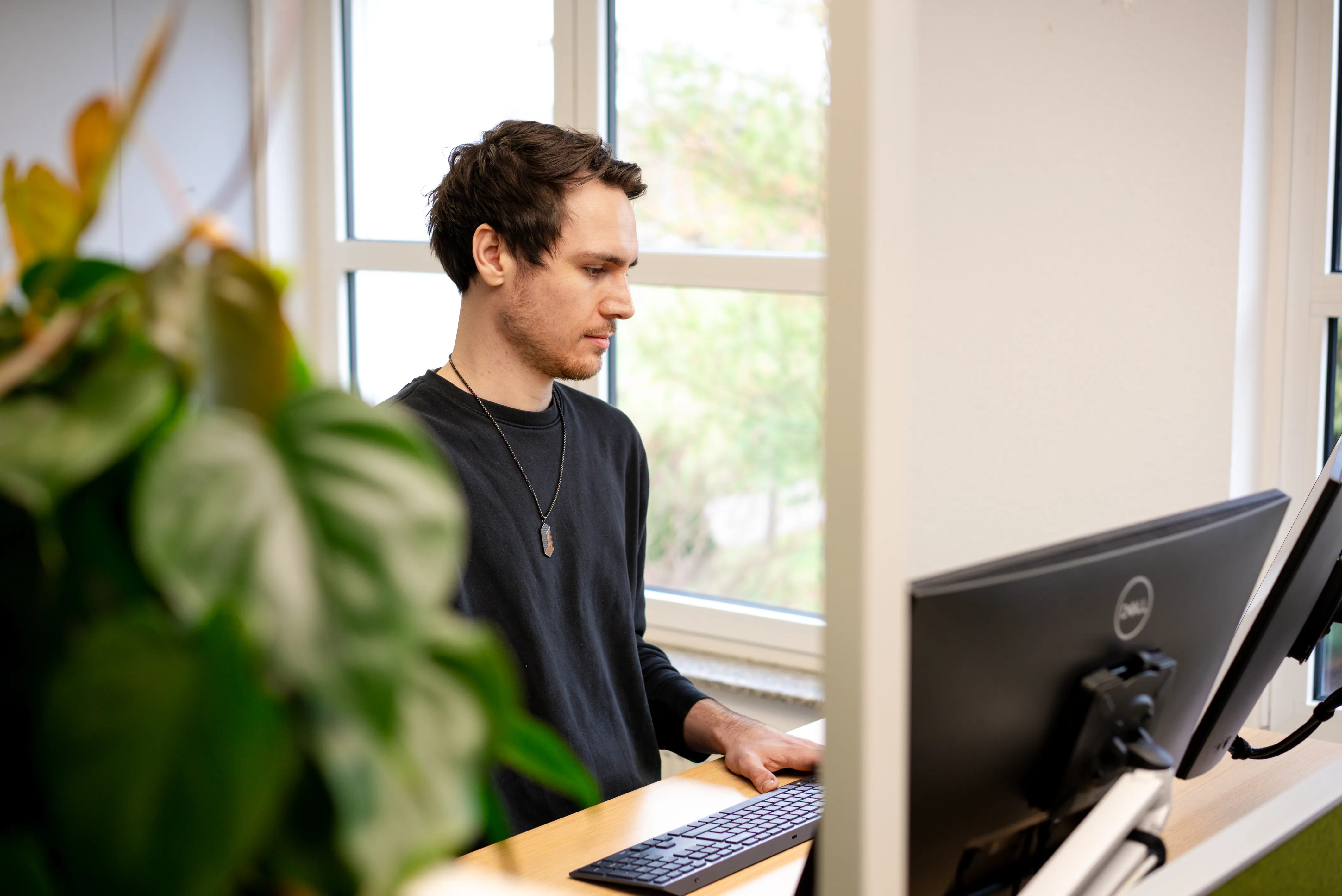 Junge Frau sitzt lächelnd an einem Schreibtisch mit Laptop, bereit für neue Herausforderungen im Beruf.