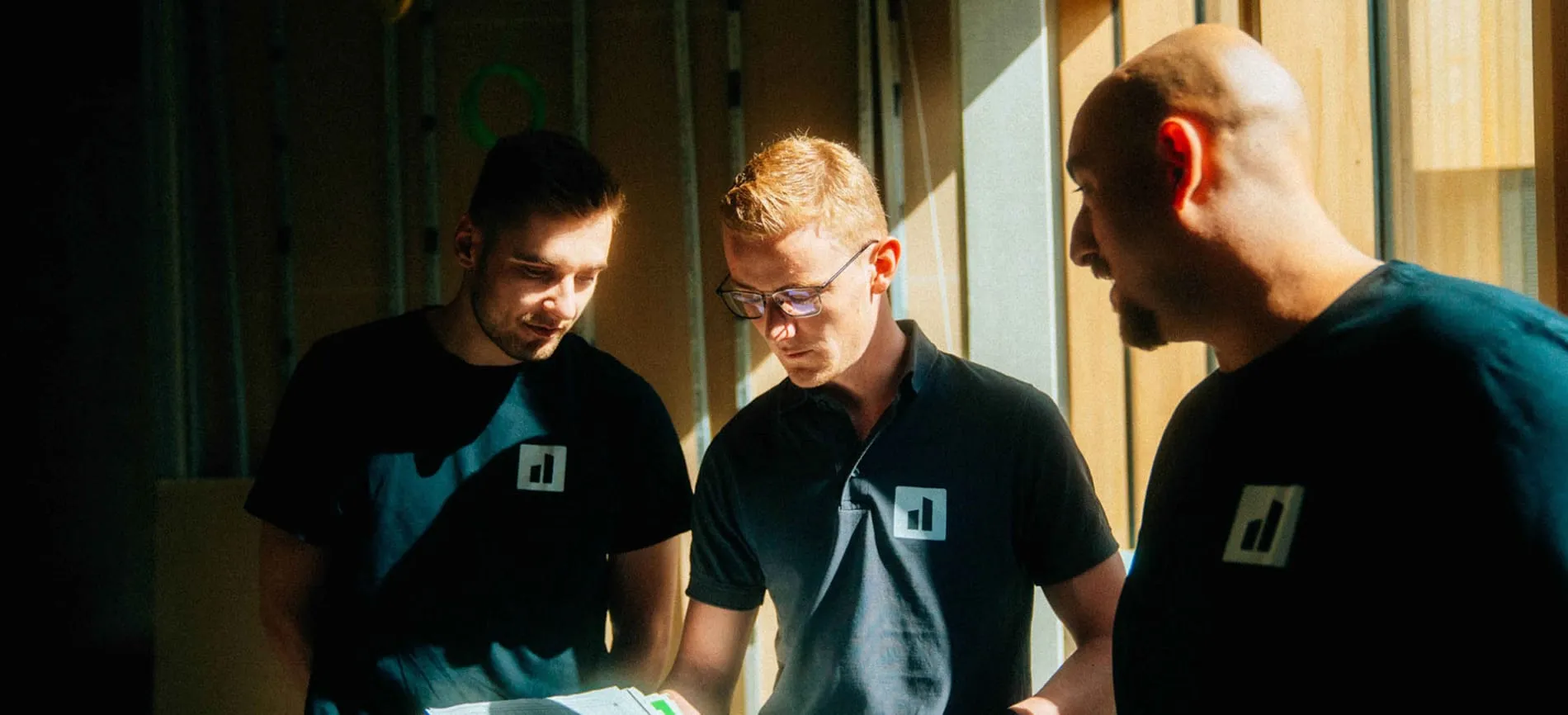 Drei Kollegen besprechen gemeinsam Pläne im Sonnenlicht – starte Du Deine Karriere im Team.