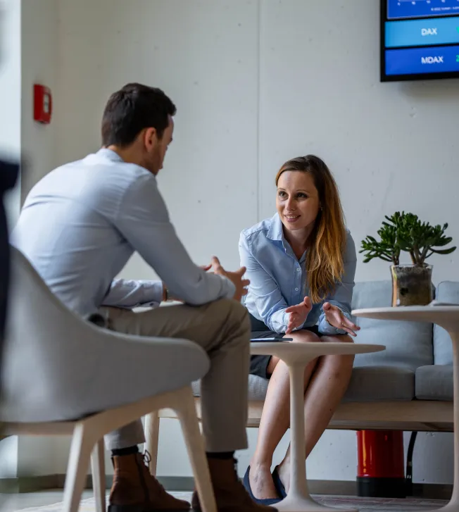 Two colleagues having a focused discussion at a desk, embodying teamwork at Deutsche Börse AG.