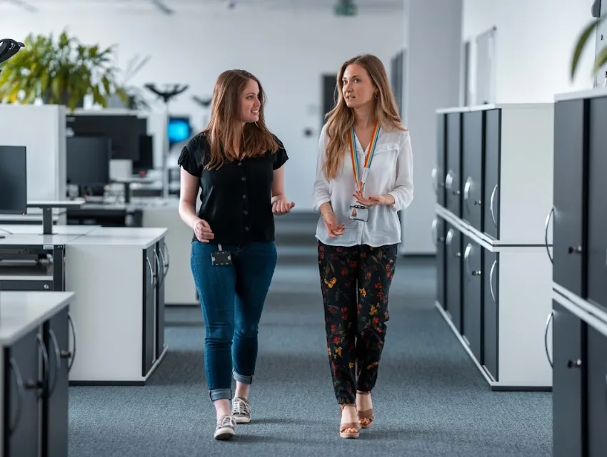 Two colleagues chatting and walking in a bright, modern office at Deutsche Börse Group.