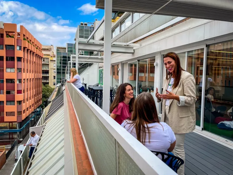 Team members chatting and enjoying a sunny break on a modern office terrace at DocMorris.