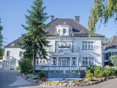 Ein elegantes Gebäude des Pflegeheims Haus Emilie in Völklingen mit gepflegtem Garten, das zum Domus Cura GmbH gehört.