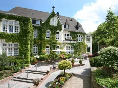 Die charmante, von Efeu bewachsene Einrichtung Haus Oebntraut in Stromberg mit gepflegtem Garten und Sitzbereich im Freien. Perfekt für eine Karriere im Gesundheitswesen.