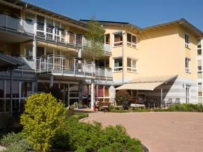 Außenansicht des modernen Pflegeheims "Glück im Winkel" in Neunkirchen mit Garten und Terrasse bei sonnigem Wetter.