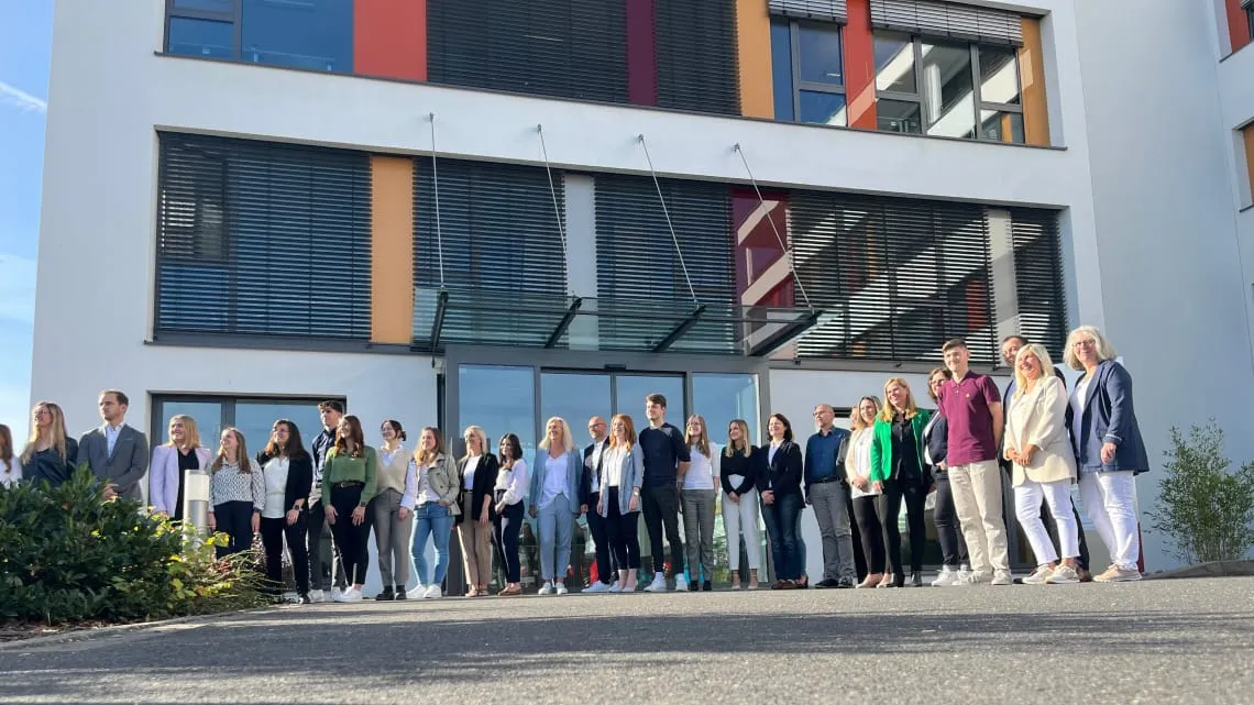 Eine Gruppe von DORNBACH-Mitarbeitenden steht gemeinsam vor dem Bürogebäude und blickt freundlich in die Kamera.