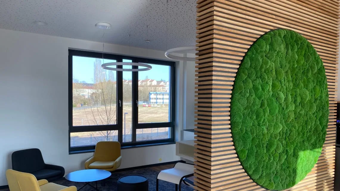Moderner, heller Loungebereich bei DORNBACH mit grüner Mooswand und gemütlichen Sesseln für Deine Pause.