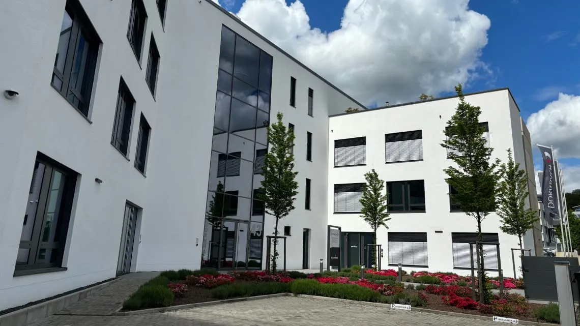 Modernes Bürogebäude von DORNBACH GmbH mit gepflegtem Eingangsbereich und Firmenflagge bei schönem Wetter.