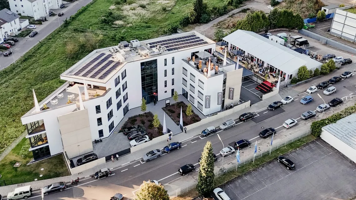 Luftaufnahme des modernen Firmengebäudes von DORNBACH GmbH mit Dachterrassen und Parkplätzen, ideal für deinen Karrierestart.