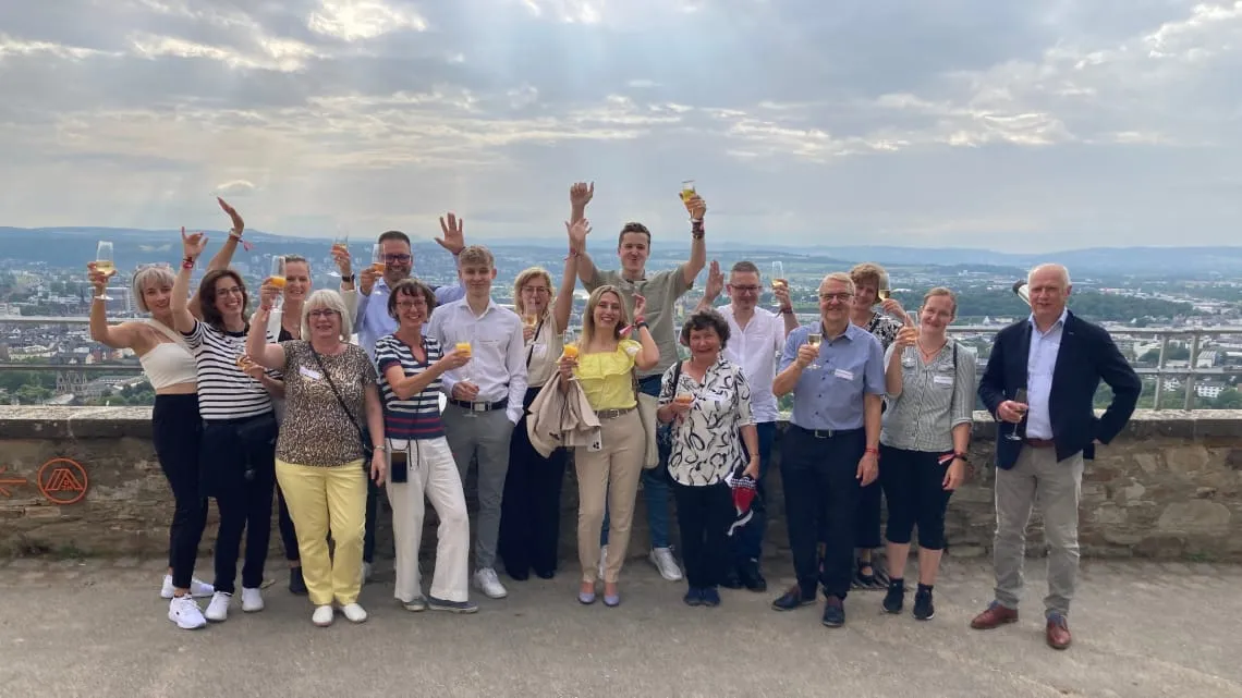 Eine fröhliche Gruppe von DORNBACH-Kollegen stößt gemeinsam draußen mit Getränken an und genießt die Aussicht.
