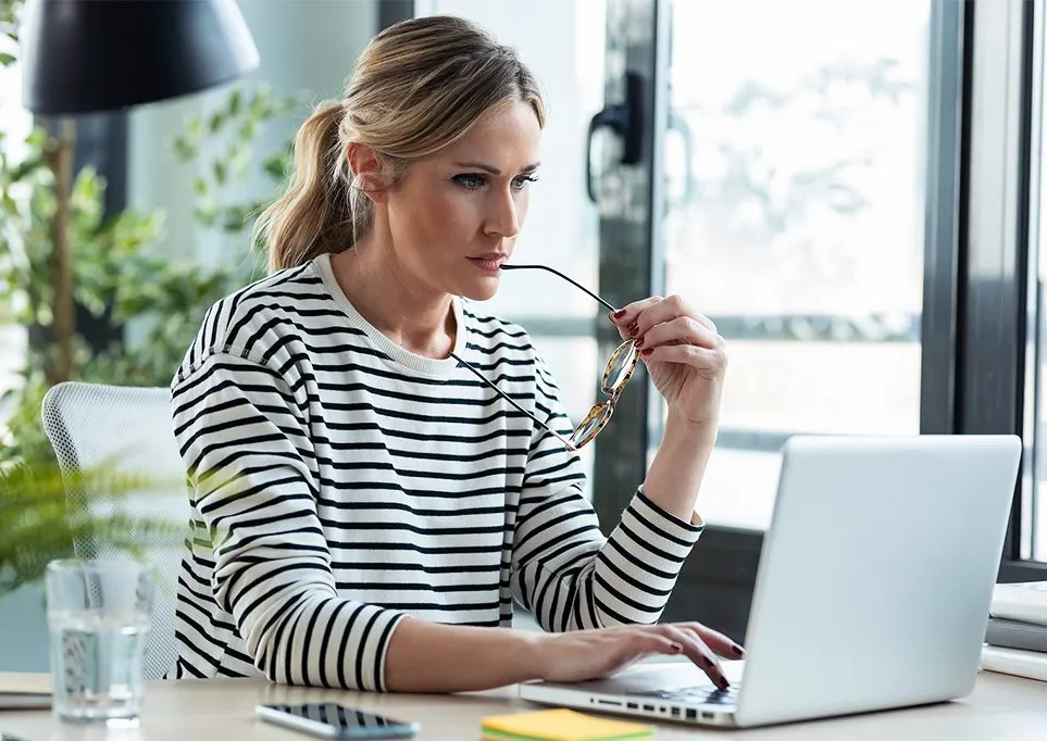 Eine Mitarbeiterin der IT-Abteilung arbeitet konzentriert an einem Laptop in einem modernen Büro.