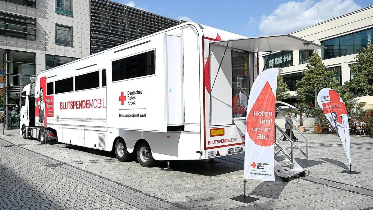 Ein modernes Blutspendemobil vom DRK Blutspendedienst West wartet auf Dich vor einem Bürogebäude.